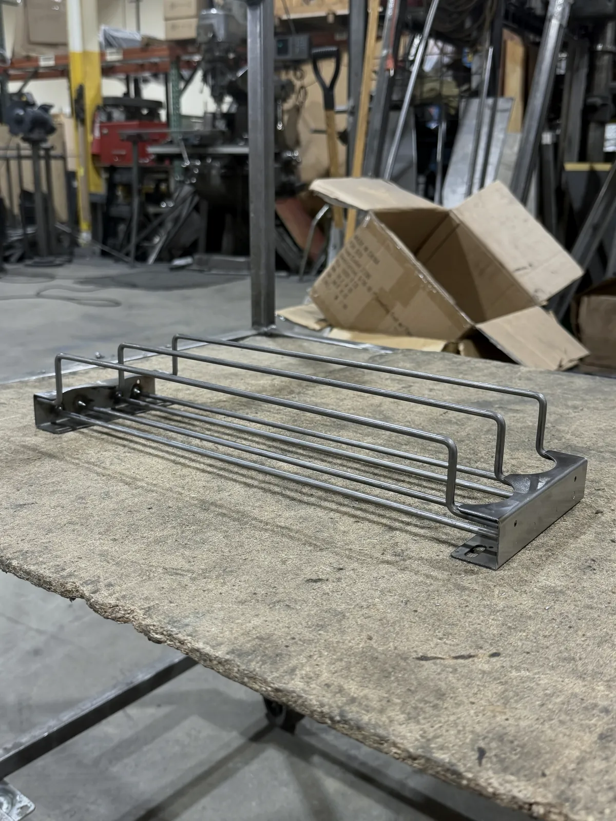Wire drink shelf pusher showing the formed end bracket and mounting holes