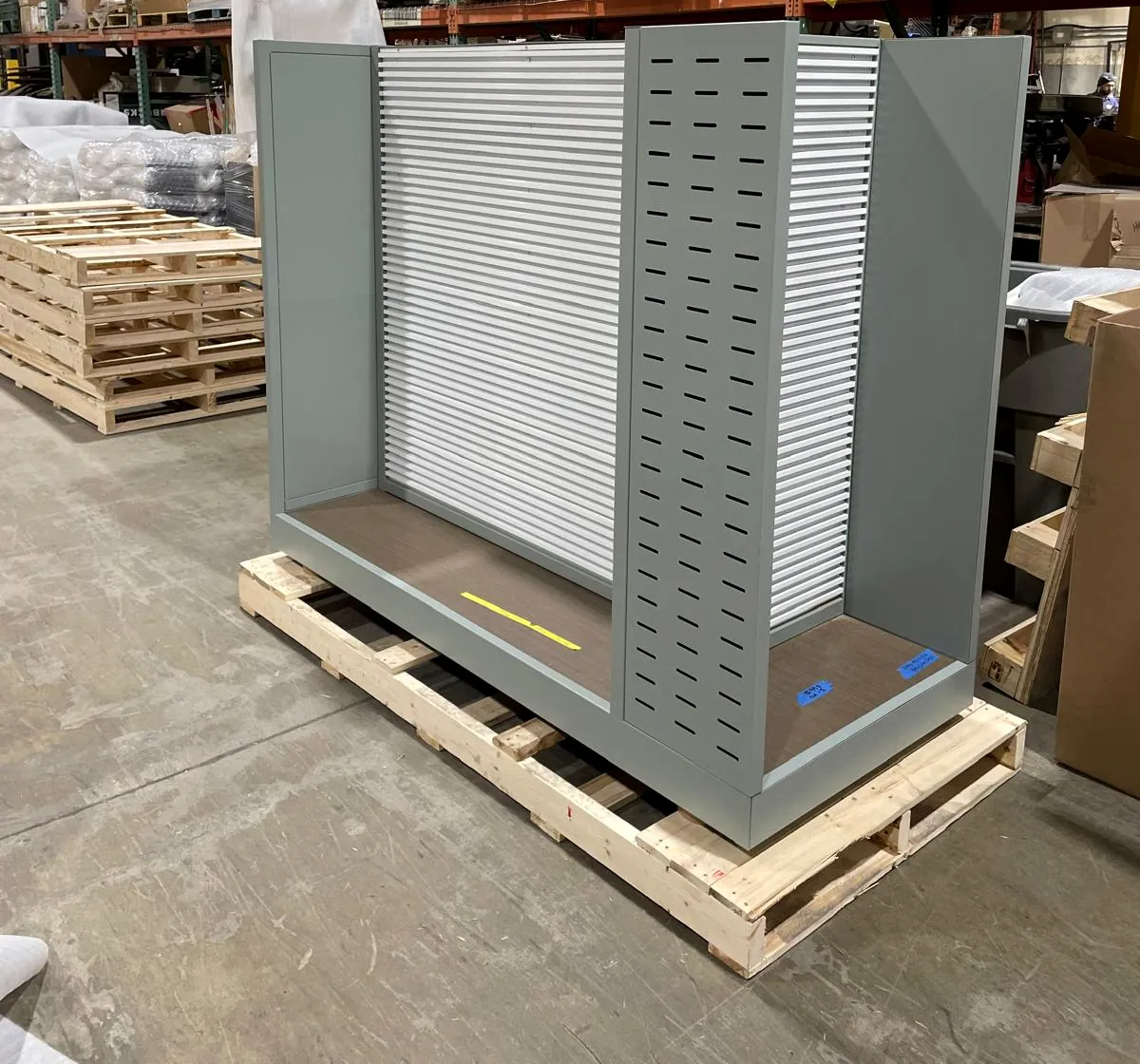 Four-way gondola store fixture powder coated in sage green, on a pallet